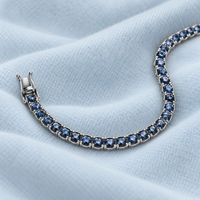 Coroné blue sapphire tennis bracelet and its clasp on pale ice-blue cashmere