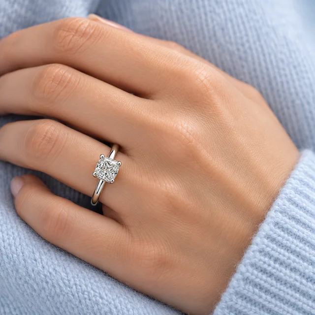 Essential PS Solitaire Ring worn on the ring finger beside pale-blue cashmere