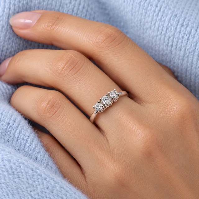 Trilogy Forever Ring worn on the ring finger beside pale-blue cashmere