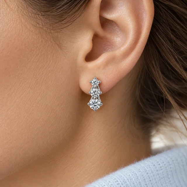 One Trilogy Scalare Flower Earring worn on the earlobe beside pale-blue cashmere